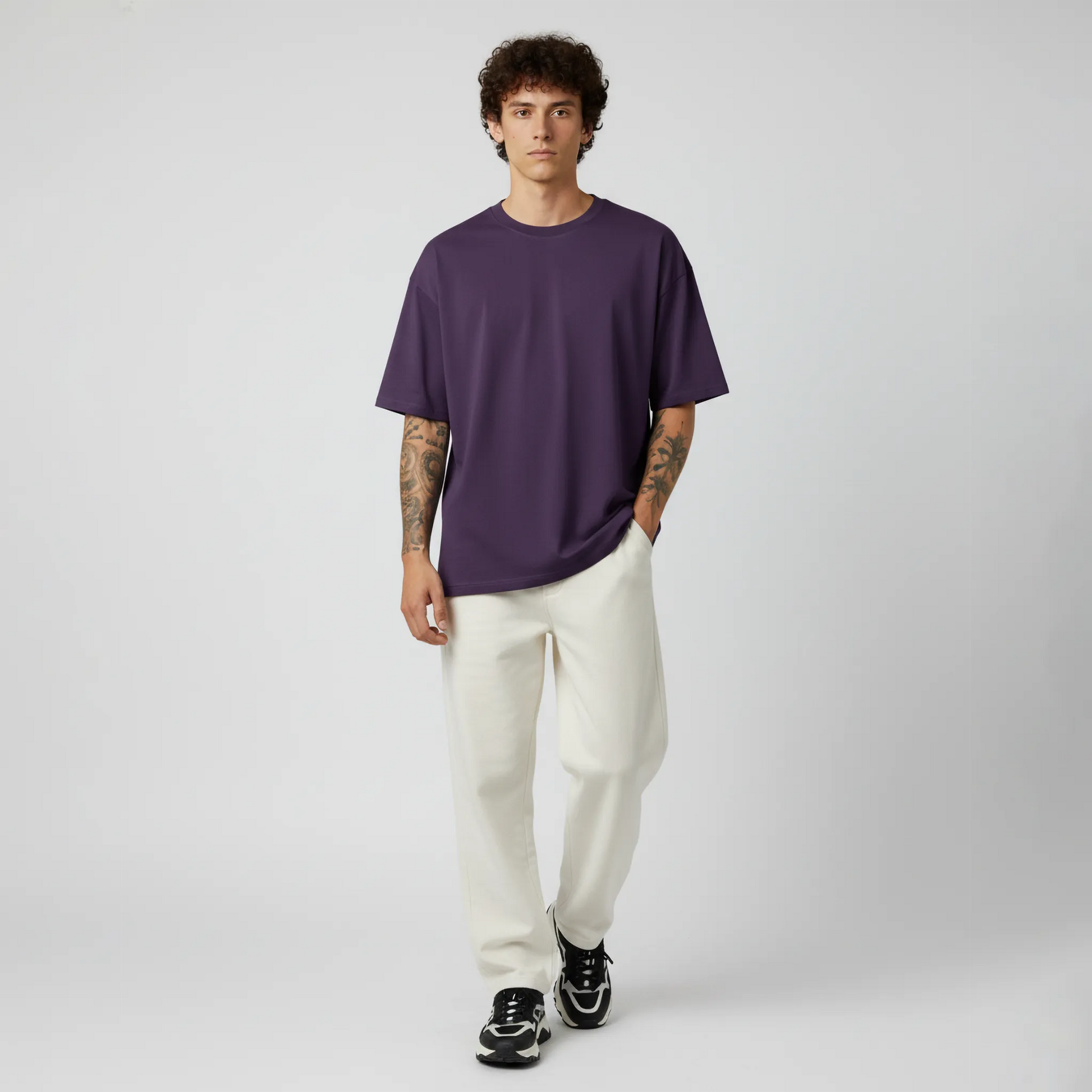 Man wearing a purple t-shirt and white pants on a gray background
