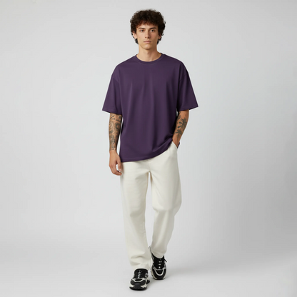 Man wearing a purple t-shirt and white pants on a gray background