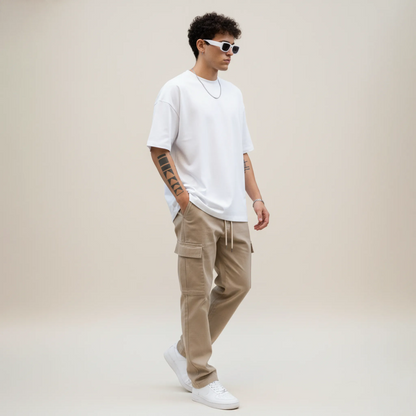 Man wearing a white t-shirt, beige cargo pants, and white sneakers on a plain background