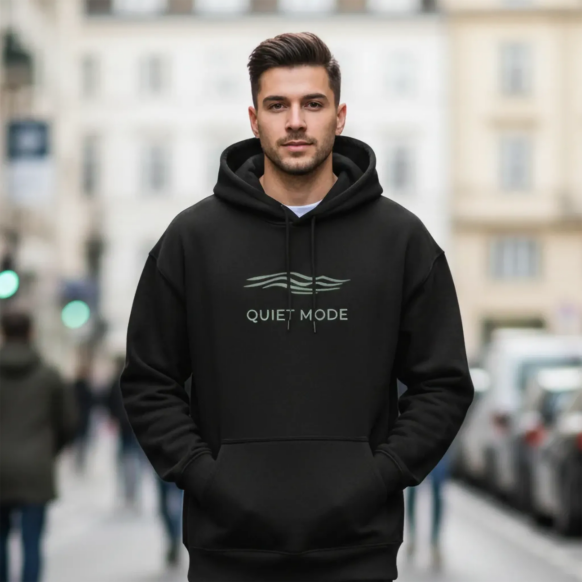 Man wearing a black hoodie with 'Quiet Mode' text on a blurred city street background