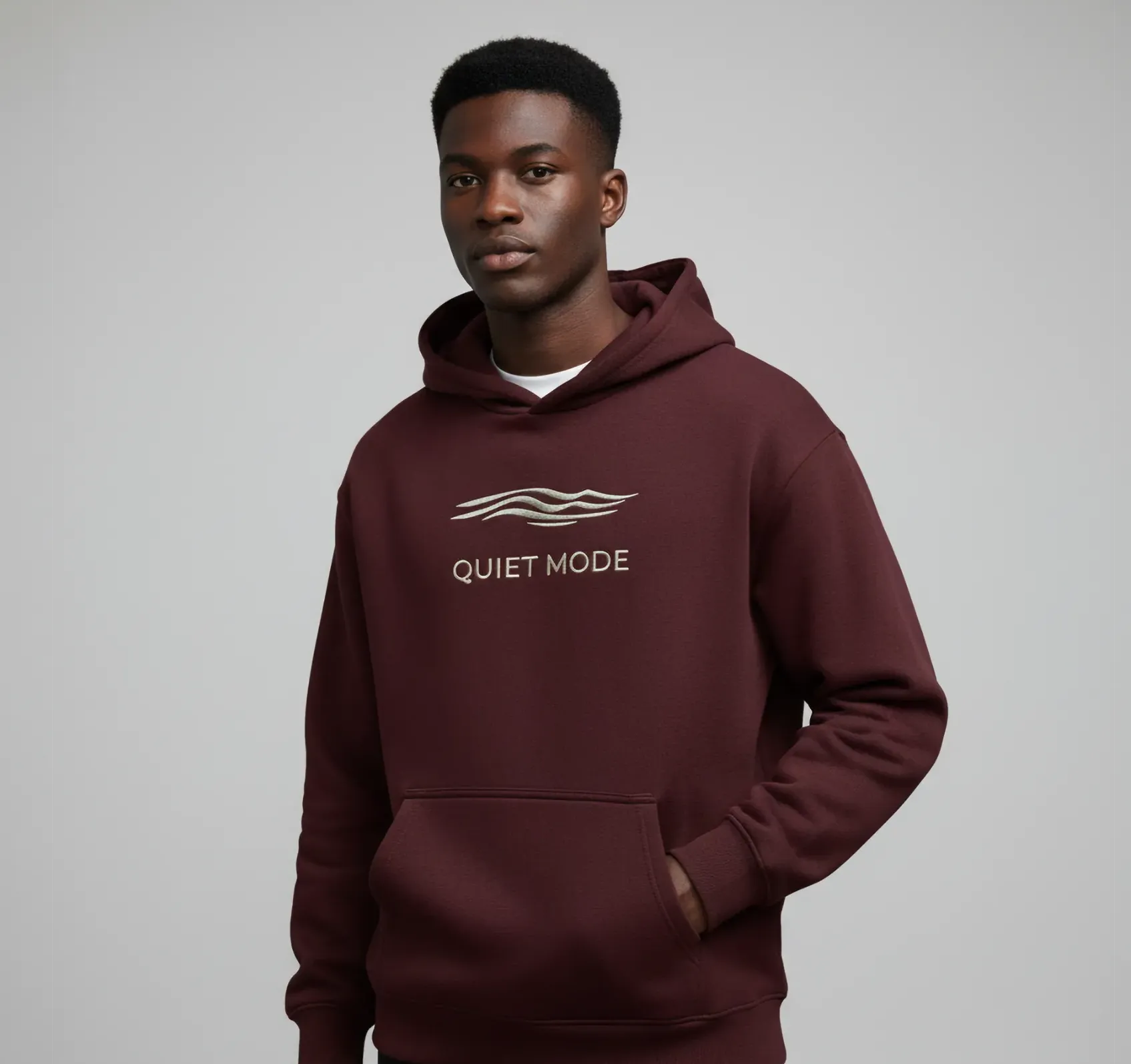 Person wearing a maroon hoodie with 'Quiet Mode' text and wave design on a gray background