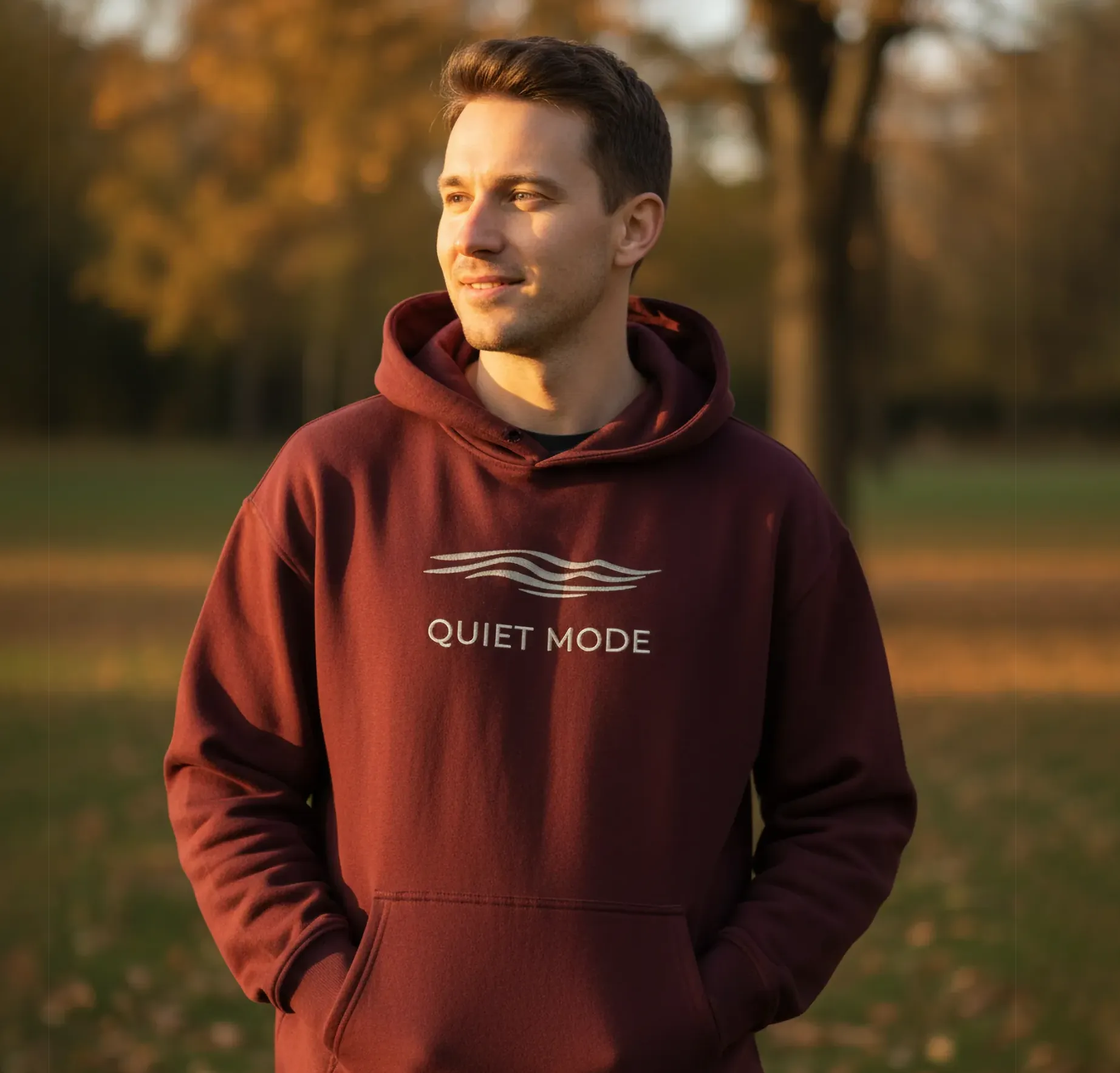 Man wearing a maroon hoodie with 'Quiet Mode' text outdoors