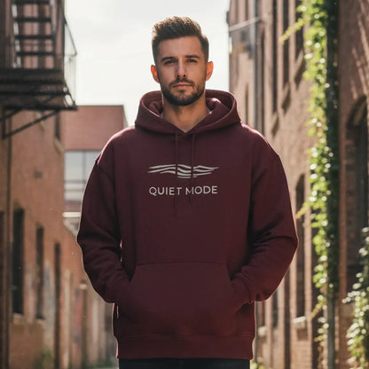 Man wearing a maroon hoodie with 'QUIET MODE' text in an urban setting