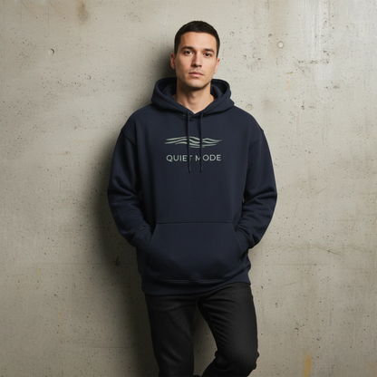 Man wearing a navy hoodie with 'QUIET MODE' text against a textured wall